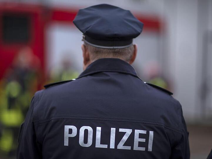 Polizisten stehen vor einem Polizeifahrzeug. Foto: Jens Büttner/zb/dpa