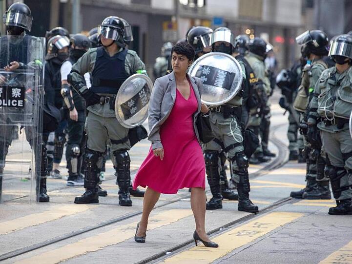 Alltag in Hongkong: Eine Frau geht an Polizisten vorbei, die eine Straße sichern.