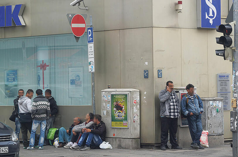 Eine Gruppe Männer wartet an der Kreuzung Landwehrstraße/Goethestraße auf Arbeit.