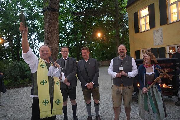 Kurz vor einem kleinen Regenguss segnet Pfarrer Rainer Maria Schießler die Menterschwaige am Isarhochufer und überreicht dem Wirtepaar Till und Pamela Weiß ein Kreuz.