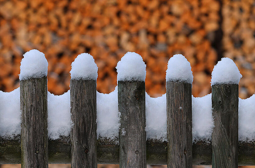 Mit kleinen Schneehauben bedeckt sind die Latten eines Zaunes am 22.11.2015 in Kaufbeuren (Bayern).