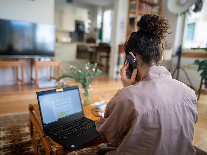 Eine Frau nimmt aus ihrem Wohnzimmer an einer Telefonkonferenz teil. Foto: Sebastian Gollnow/dpa