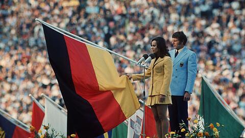 Fünfkämpferin Heidi Schüller spricht für die im Stadion versammelten Sportler den Olympischen Eid. Hinter ihr der Fahnenträger der deutschen Mannschaft Detlef Lewe.