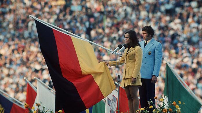 Fünfkämpferin Heidi Schüller spricht für die im Stadion versammelten Sportler den Olympischen Eid. Hinter ihr der Fahnenträger der deutschen Mannschaft Detlef Lewe.
