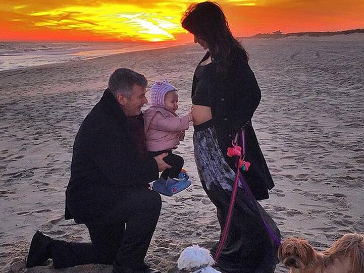 Familienglück am Strand: Alec Baldwin mit Tochter Carmen, die den Bauch der schwangeren Mutter streichelt
