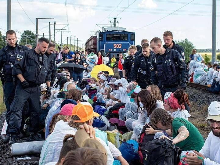 Unter Polizeibeobachtung aus nächster Nähe: Aktivisten blockieren am Freitag die Gleise der Kohle-Transportbahn.