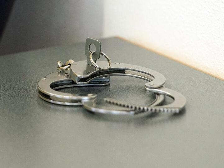 Handschellen liegen auf einem Tisch. Foto: Armin Weigel/dpa/Symbolbild