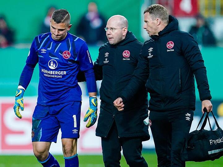Nürnbergs Torwart Patric Klandt (l) verlässt verletzt das Spielfeld. Foto: Uwe Anspach/dpa