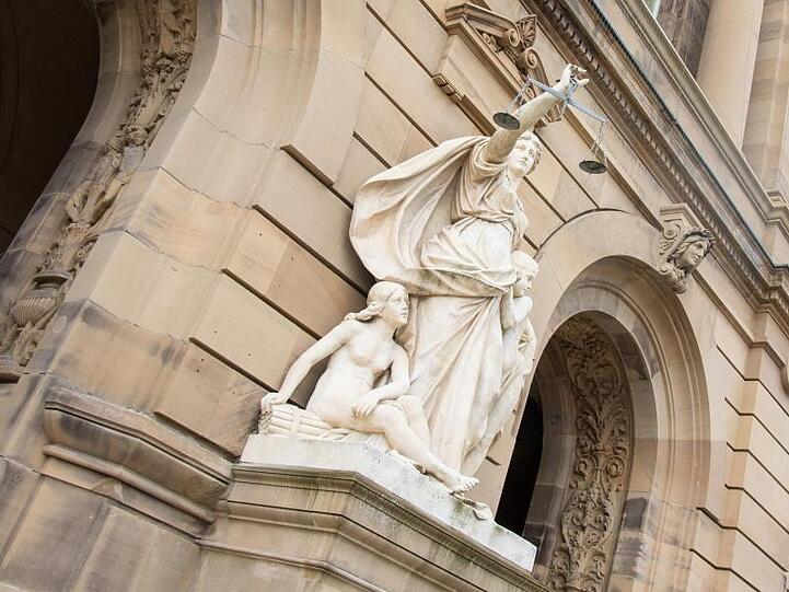 Vor dem Gerichtsgebäude hält eine Statue der Justitia eine Waagschale. Foto: Stefan Puchner/dpa/Archivbild