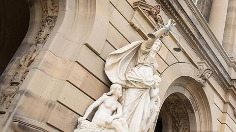 Vor dem Gerichtsgebäude hält eine Statue der Justitia eine Waagschale. Foto: Stefan Puchner/dpa/Archivbild