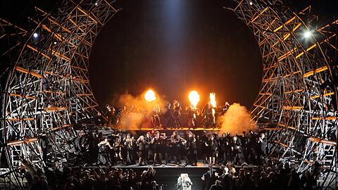 René Pape (links), Joseph Calleja (auf dem Stuhl) und der Chor der Bayerischen Staatsoper feiern in Boitos &bdquo;Mefistofele&ldquo; die Walpurgisnacht.