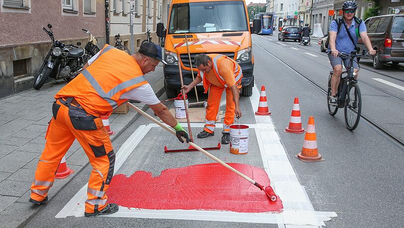 Mitarbeiter der Stadt bringen den neuen roten Radlstreifen auf der Fraunhoferstraße an. Mitarbeiter der Stadt bringen den neuen roten Radlstreifen auf der Fraunhoferstraße an.