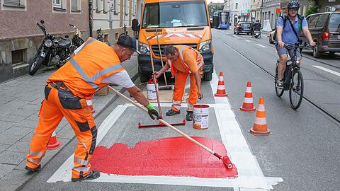 Mitarbeiter der Stadt bringen den neuen roten Radlstreifen auf der Fraunhoferstraße an.