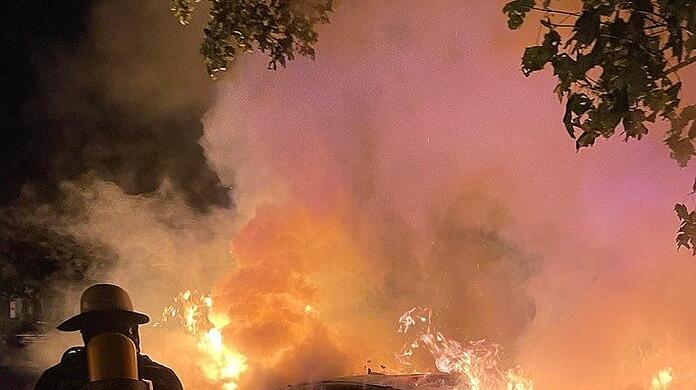 Ein Feuerwehrmann löscht in der Nacht auf Freitag am Mariahilfplatz den Mercedes.  Branddirektion