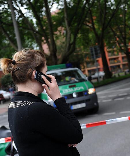 Eine Frau telefoniert in Köln vor einer wegen einer Bombenentschärfung gesperrten Straße.