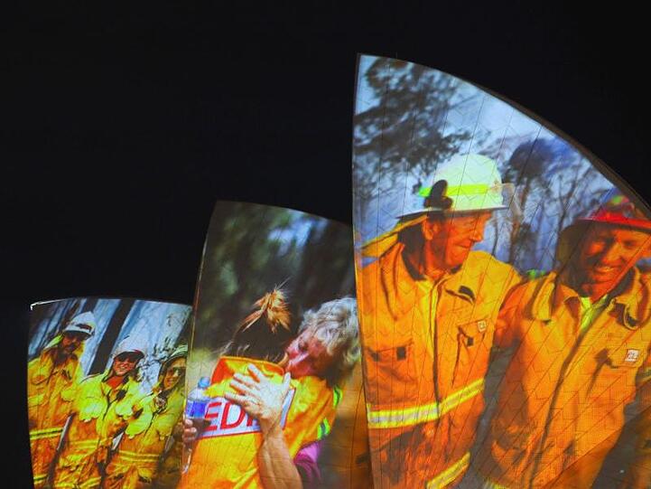 Symbolischer Dank an die Einsatzkräfte in Sydney: Auf die großen Segel des Opernhauses werden als Zeichen der Solidarität Bilder von Feuerwehrleuten projiziert.