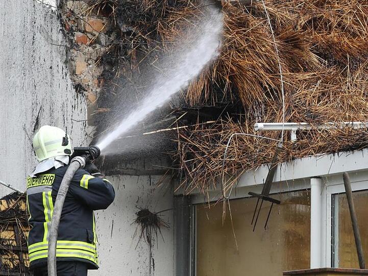 Ein Feuerwehrmann löscht Glutnester im Dachstuhl des ausgebrannten Ostseehotels.
