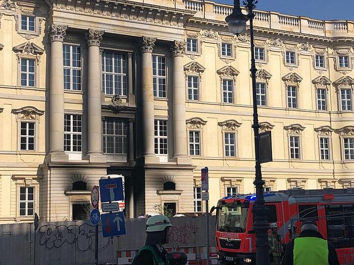 Ein Feuerwehrfahrzeug steht vor dem Berliner Humboldt Forum. Teile der Fassade sind schwarz vom Ruß.