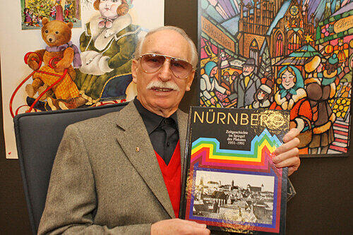 Fritz Henry Oerter mit dem neuen Buch. Im Hintergrund Plakate für Spielzeugmuseum (1986) und Christkindlesmarkt (1988).