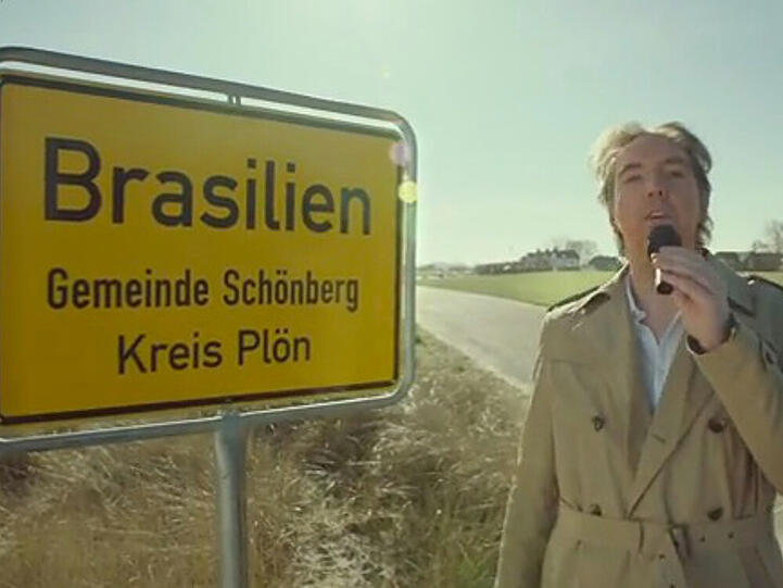 Olli Schulz am Ortsschild von Brasilien, Schleswig-Holstein