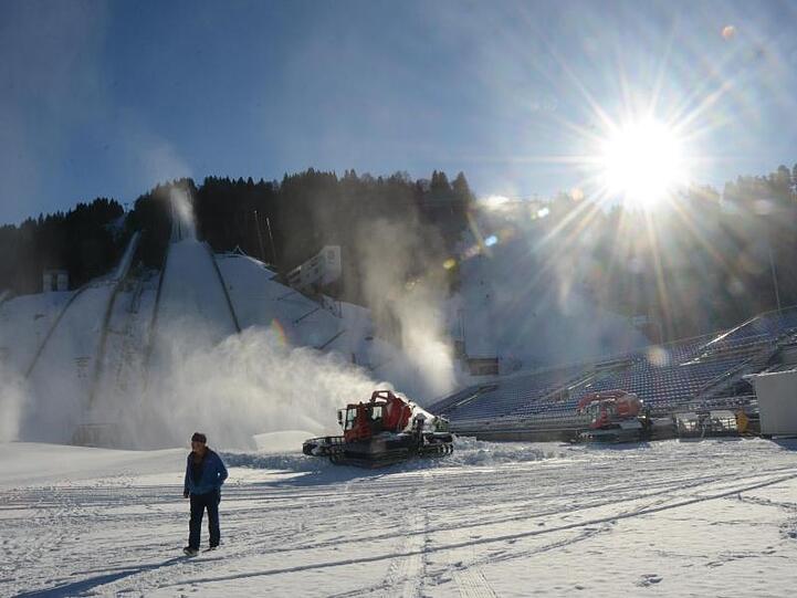 Ein Mann steht am Fuß der großen Skisprungschanze vor einer Beschneiungsanlage. Foto: Hartmut Reeh