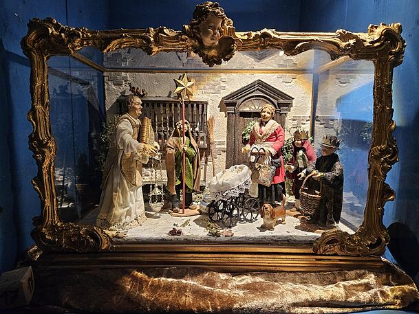 Diese Kastenkrippe mit hübschen goldenem Schnörkelrahmen zeigt eine Sternsinger-Szene.