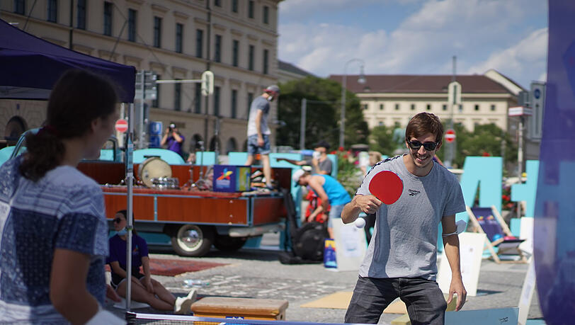 Na, erwischt er den kleinen Spielball noch? Spaßig schaut's auf jeden Fall aus, dieses Tischtennis-Spiel mitten in der Stadt.