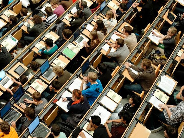 Studenten sitzen in einem großen Hörsaal der Technischen Universität (TUM). Foto: Peter Kneffel/Archivbild