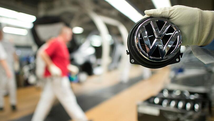 Ein Mitarbeiter zeigt in Wolfsburg ein Volkswagen-Logo. Foto: Foto: Julian Stratenschulte Ein Mitarbeiter zeigt in Wolfsburg ein Volkswagen-Logo. Foto: Foto: Julian Stratenschulte