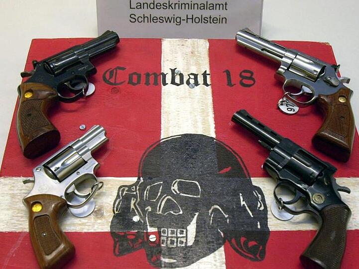 Sichergestellte Waffen und ein Schild der Neonazi-Gruppierung "Combat 18" bei einer Pressekonferenz der Kieler Kripo.