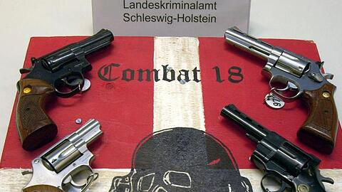 Sichergestellte Waffen und ein Schild der Neonazi-Gruppierung "Combat 18" bei einer Pressekonferenz der Kieler Kripo.