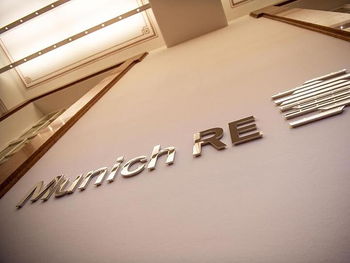 Das Logo von Munich Re an einer Wand. Foto: Lino Mirgeler/Archivbild