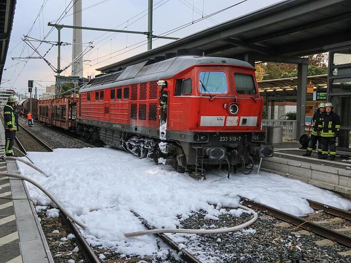 Einsatzkräfte der Feuerwehr Erlangen löschen mit Löschschaum eine Diesellok eines Güterzuges, die im Fahrwerksbereich Feuer gefangen hatte. Foto: News5