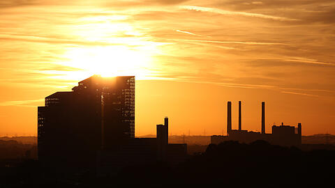Die Sonne glüht durch die Highlight Towers, rechts das Heizwerk Nord.