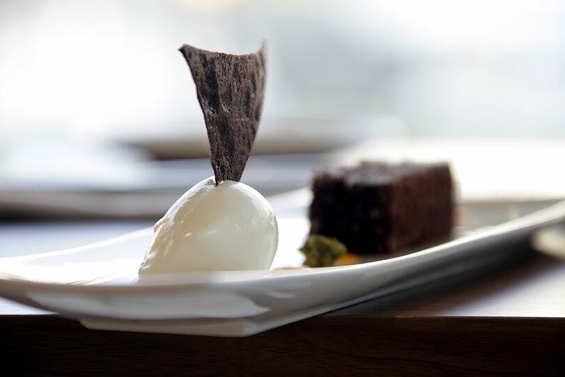 Torta Caprese mit Safran, Passionsfrucht und Chinotto-Eis: &bdquo;Chinotto&ldquo;, das ist eine italienische Kräuterlimonade. Natürlich begleitet nicht sie die finale Gaumenexplosion, sondern eine 2011 Scheurebe Spätlese vom Weingut Hauck.