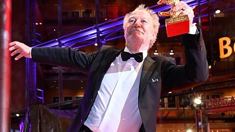 Nicolas Philibert tanzt mit seinem Goldenen Bären auf dem Roten Teppich der Berlinale