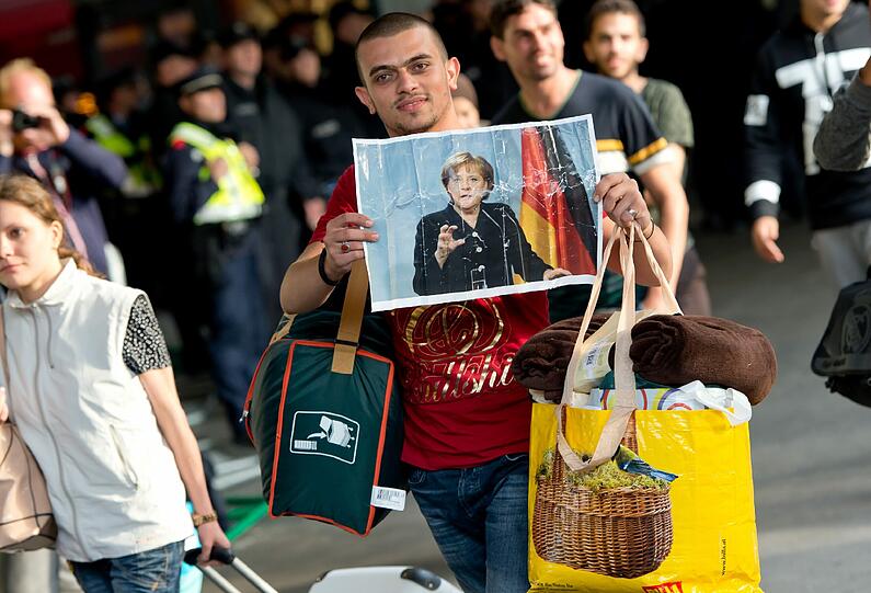 Hoffnungsort Deutschland: Ein Flüchtling zeigt am Münchner Hauptbahnhof ein Foto von Angela Merkel.