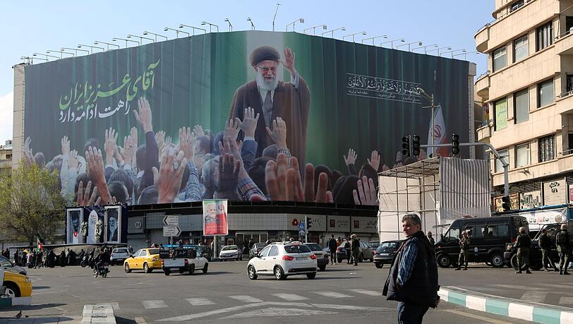 Passanten am Enghelab Square in Teheran vor einer Darstellung des getöteten Ajatollah Ali Chamenei. Passanten am Enghelab Square in Teheran vor einer Darstellung des getöteten Ajatollah Ali Chamenei.
