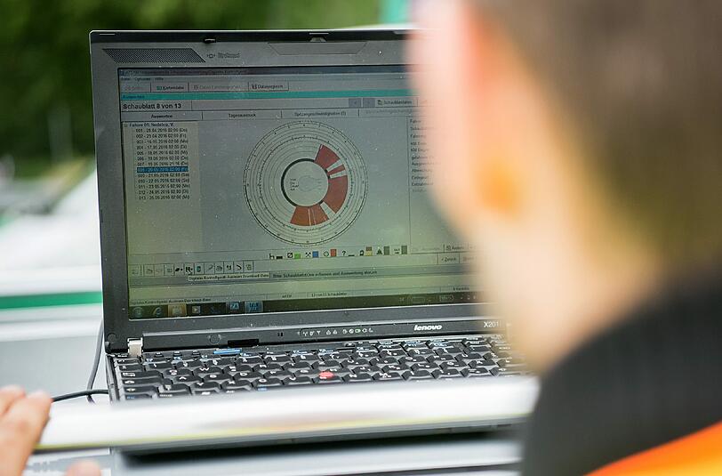 Ein Polizist schaut bei einer LKW-Kontrolle auf einen Laptop mit den Daten über die Fahrzeiten eines LKW-Fahrers. Foto: Sebastian Gollnow