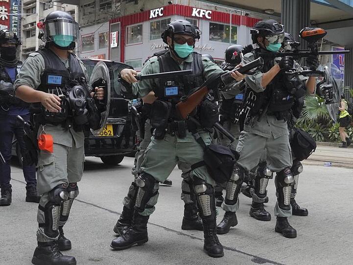 Sicherheitskräfte feuern Tränengas ab, während Hunderte Demonstranten bei einem pro-demokratischen Protest gegen die nationale Sicherheitsgesetzgebung Pekings durch Hongkongs Stadtzentrum laufen.