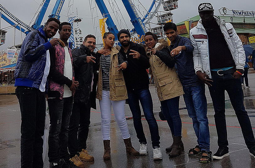 Die Gruppe Geflüchteter posiert für ein Erinnerungsfoto vor dem Riesenrad.