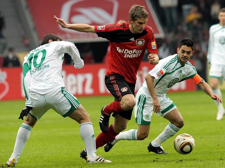 Lars Bender (M) kämpft gegen die Wolfsburger Josue (r) sowie Zvjezdan Misimovic um den Ball.