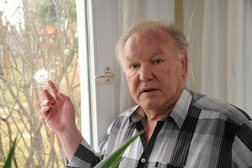 Günther S. zeigt auf das Einschussloch in seinem Fenster: Hier schlug eine Kugel durch das Glas in seine Wohnung.