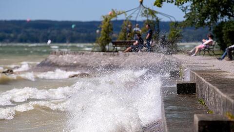 Ausflügler sitzen am Ufer des Ammersees. Foto: Sven Hoppe/dpa