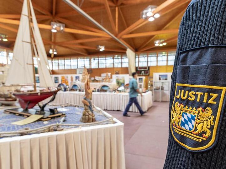 Ein JVA-Mitarbeiter steht vor den Kunstwerken. Foto: Armin Weigel/dpa
