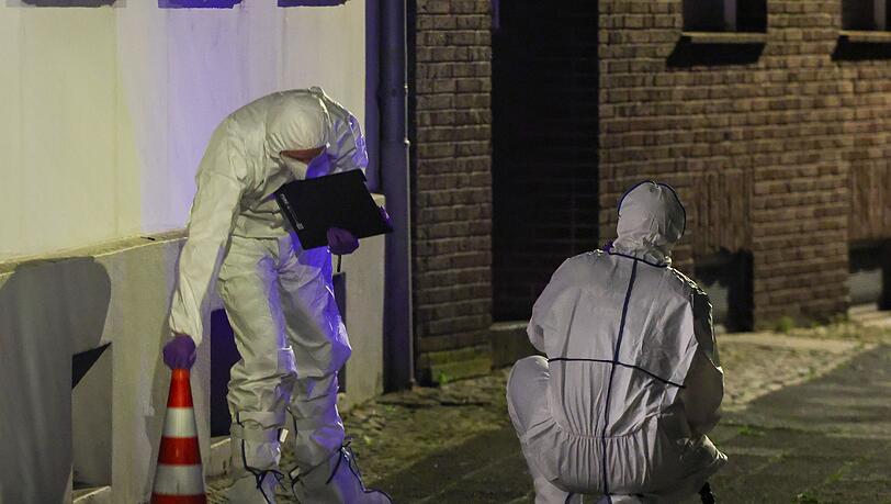 Beamte der Spurensicherung in Spurensicherungsanzügen begutachten den Tatort. Beamte der Spurensicherung in Spurensicherungsanzügen begutachten den Tatort.