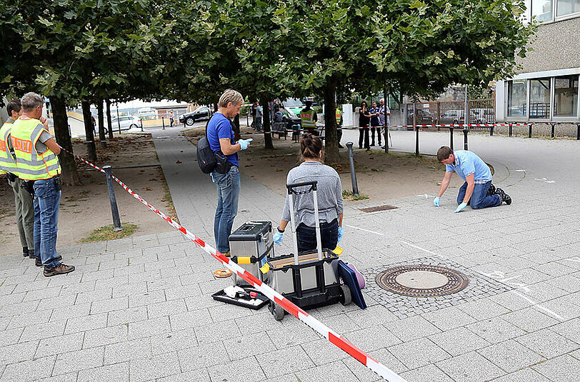 Polizisten nehmen am Tatort des unfassbaren Verbrechens Spuren auf.