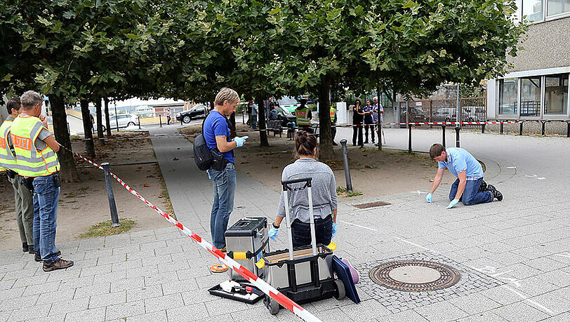 Polizisten nehmen am Tatort des unfassbaren Verbrechens Spuren auf. Polizisten nehmen am Tatort des unfassbaren Verbrechens Spuren auf.