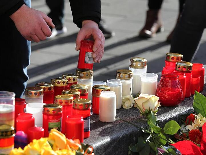 Ein Mann plaziert ein Grablicht an einem Rondell am Augsburger Königsplatz. Foto: Karl-Josef Hildenbrand/dpa/Archivbild