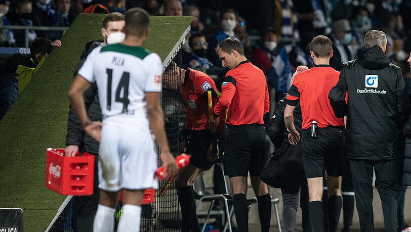 Das Schiedsrichtergespann um Benjamin Cortuns (M) verlässt das während des Spiels das Spielfeld, nachdem der Linienrichter (l) Christian Gittelmann einen Gegenstand an den Kopf bekommen hatte.